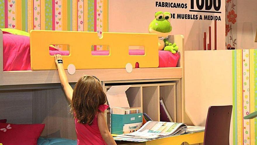 Una niña observa un dormitorio juvenil en la feria.