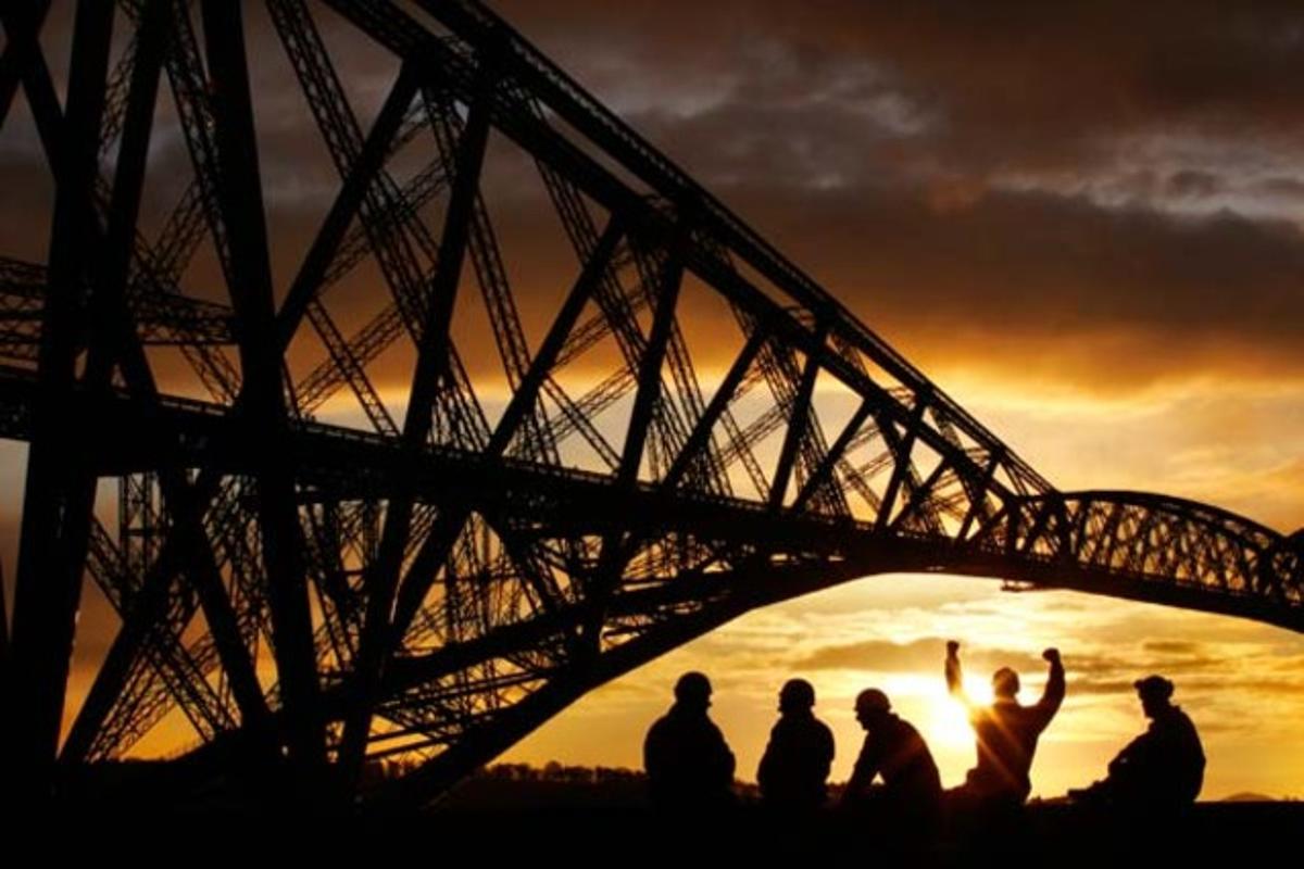 Els membres de l’equip de pintura, asseguts davant el pont al nord de Queensferry, a prop d’Edimburg (Escòcia), després d’acabar la seva restauració, que ha durat més de 10 anys.