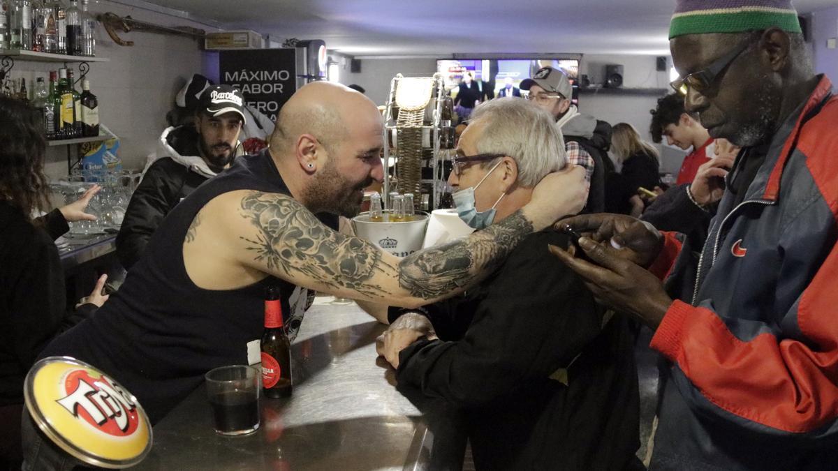 Tino, propietari del bar de Calella que ha venut part del tercer premi de la rifa de Nadal s&#039;abraça amb el seu sobre, a la barra de l&#039;establiment, el 22 de desembre de 2021