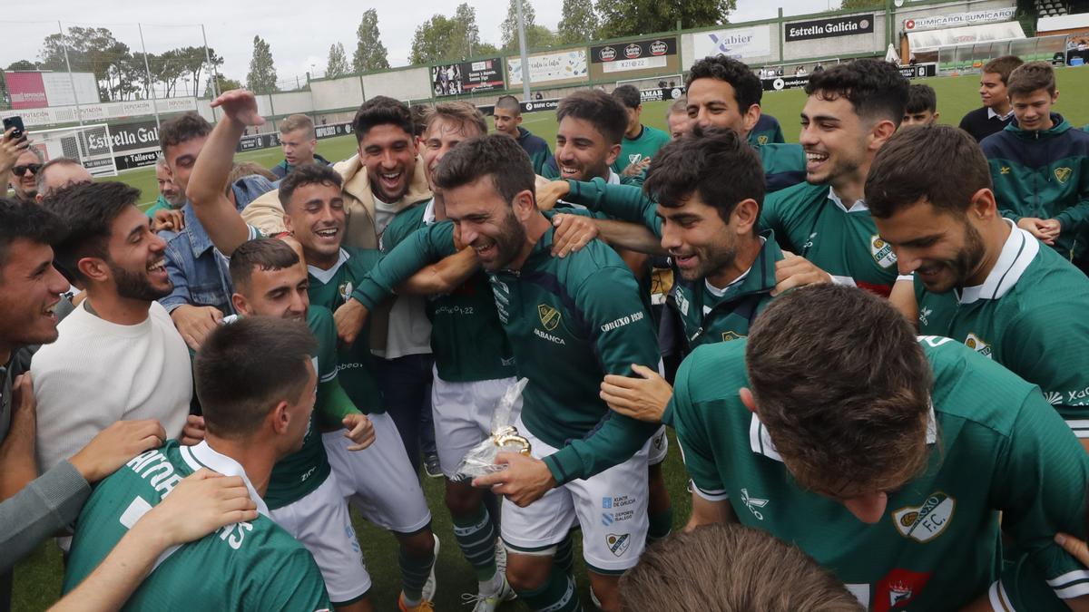 Los jugadores del Coruxo celebran su clasificación para la fase de ascenso y se preparan para mantear a Jacobo Trigo.