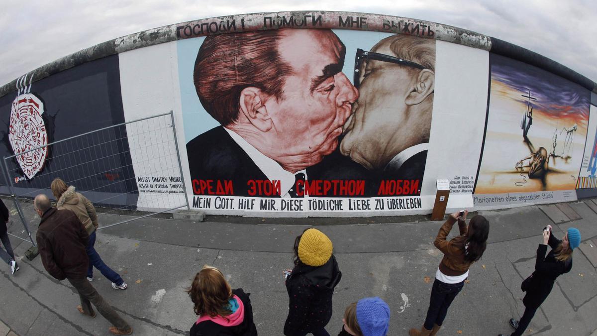 RUSO DMITRY VRUBEL EN EL MURO DE BERLIN , EN EL QUE APARECE EL ANTIGUO LIDER DE LA URSS LEONID BREZHNEV (I), BESANDO A SU HOMOLOGO DE LA REPUBLICA DEMOCRATICA ALEMANA ERICH HONECKER. Tourists look at the mural by Russian artist Dmitry Vrubel of former Soviet leader Leonid Brezhnev kissing his East German counterpart Erich Honecker, painted on a segment of East Side Gallery, the largest remaining part of the former Berlin Wall, in Berlin October 30, 2009. A 1,300 metres (4,265 ft) stretch of wall, the world's longest open-air art gallery, was decorated by 118 artists from 21 countries in 1990, but has since been damaged by the weather, exhaust fumes, vandals, and souvenir-seeking tourists. The restoration work is expected to be completed in time for the 20-year anniversary in November of the fall of the wall which once divided communist East Berlin from capitalist west Berlin. REUTERS/Fabrizio Bensch (GERMANY ENTERTAINMENT SOCIETY POLITICS ANNIVERSARY) GERMANY/