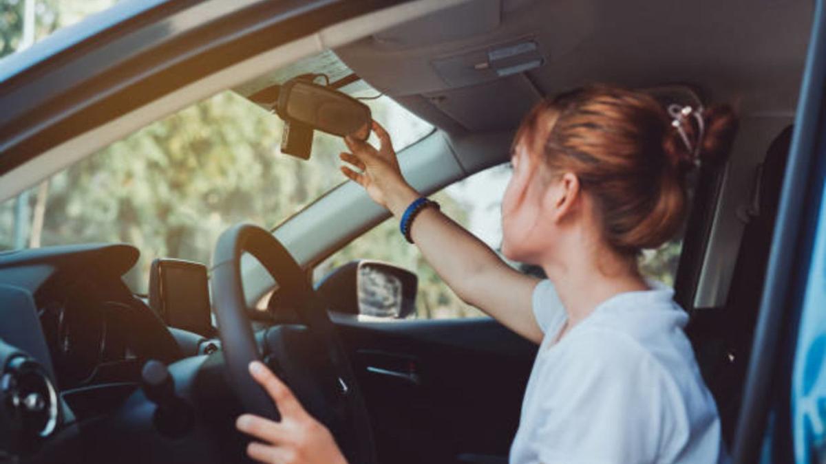 Una joven ajusta los espejos del coche antes de comenzar a conducir.
