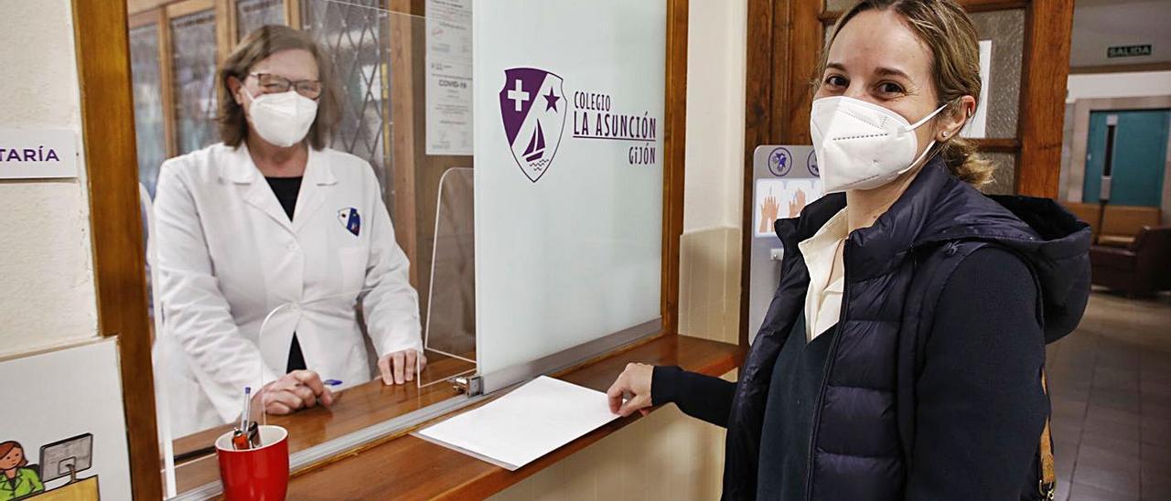 Ana Guil entrega la solicitud de plaza para su hija de 3 años a la secretaria del colegio La Asunción de Gijón, Loli Rionda. | Ángel González