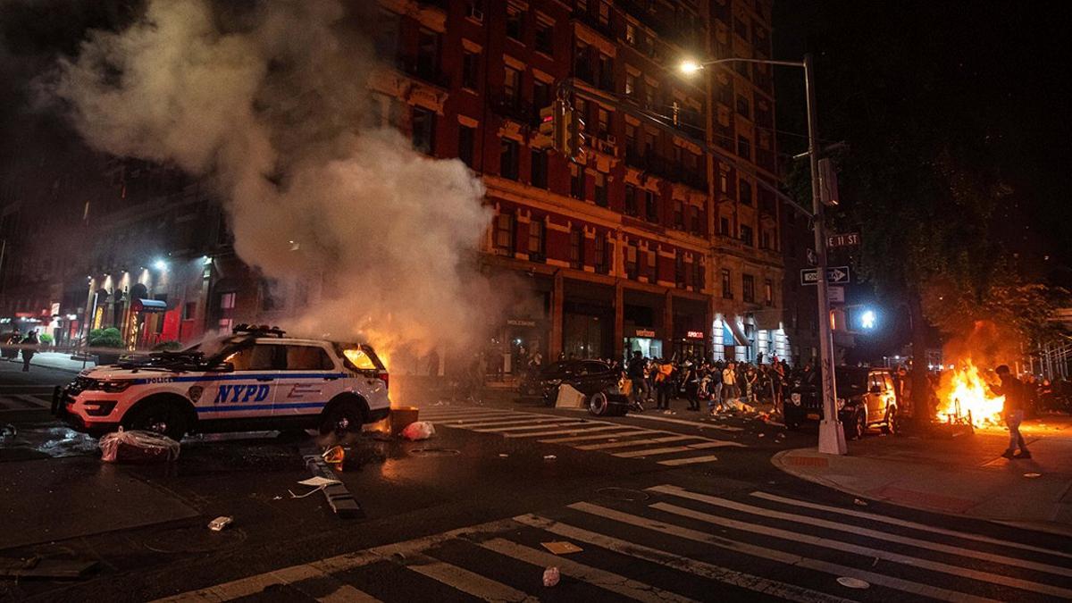 Un numeroso grupo de manifestantes observan cómo arde un coche de la policía en Manhattan, este sábado 30 de mayo, durante las protestas por la muerte de George Floyd en Minneápolis