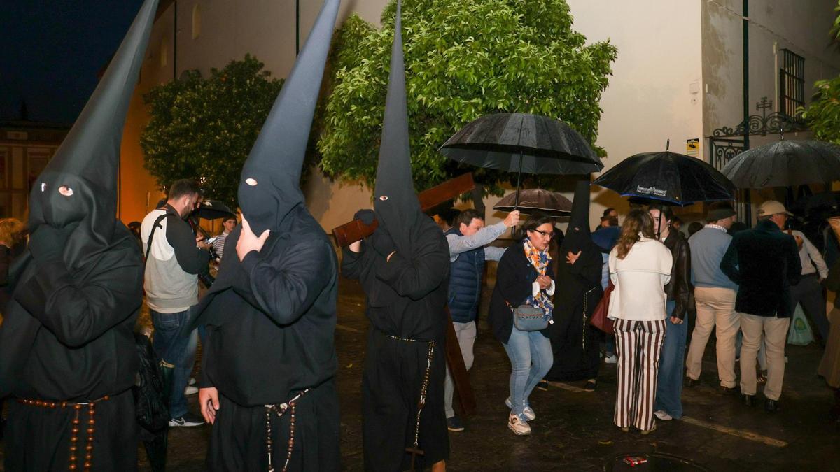 Paraguas abiertos junto a nazarenos del Vía Crucis, hermandad que ayer se quedó sin salir por la lluvia.