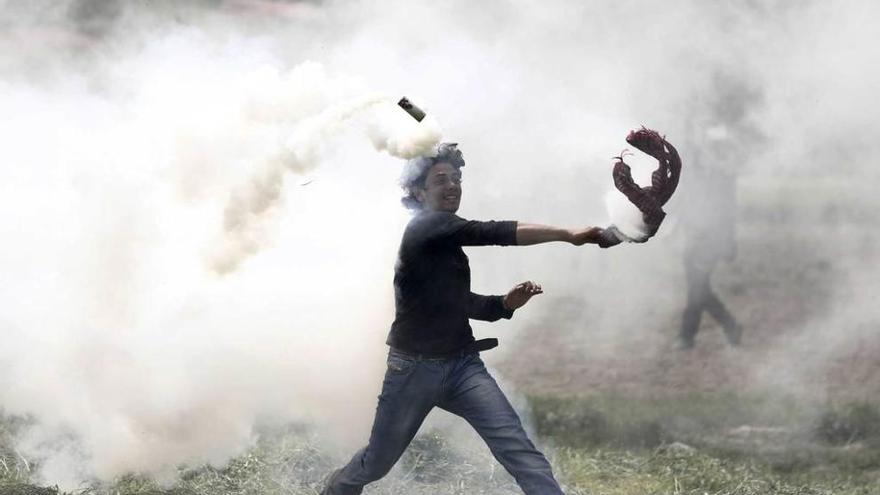 Un refugiado lanza de vuelta un bote de gas lacrimógeno en Idomeni.