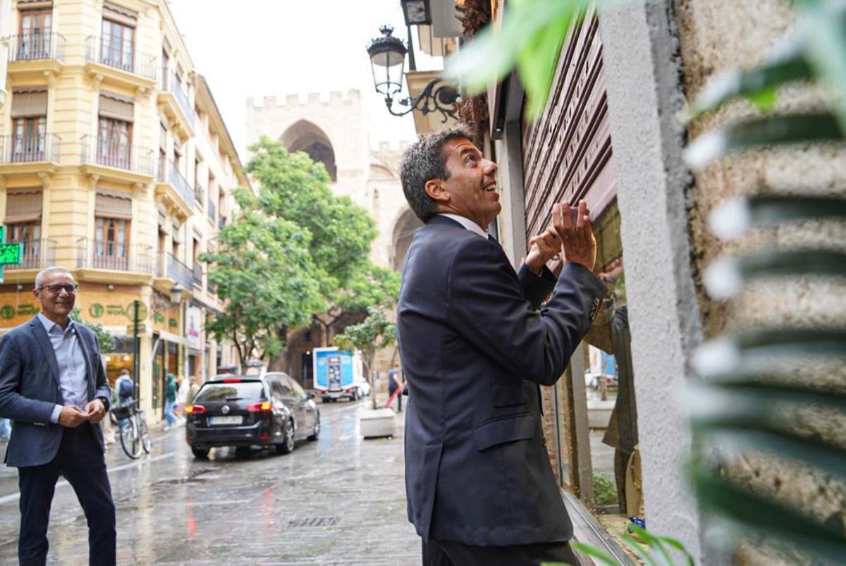 Carlos Mazón levanta la persiana de un comercio en València.