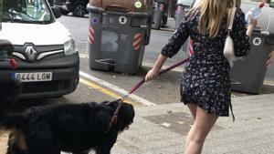 Una mujer pasea por el Eixample barcelonés con un botellín de agua para mitigar la meada de su perro sobre la acera