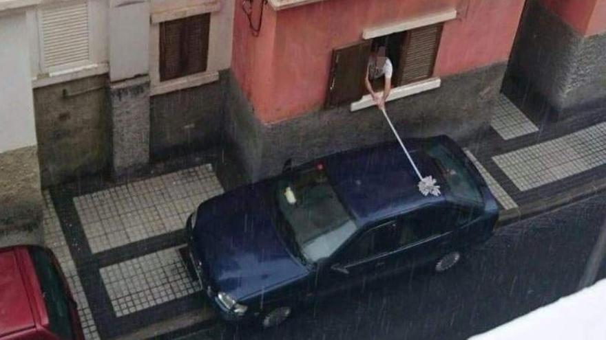 Limpiando el coche en plena lluvia... desde la ventana y con una fregona