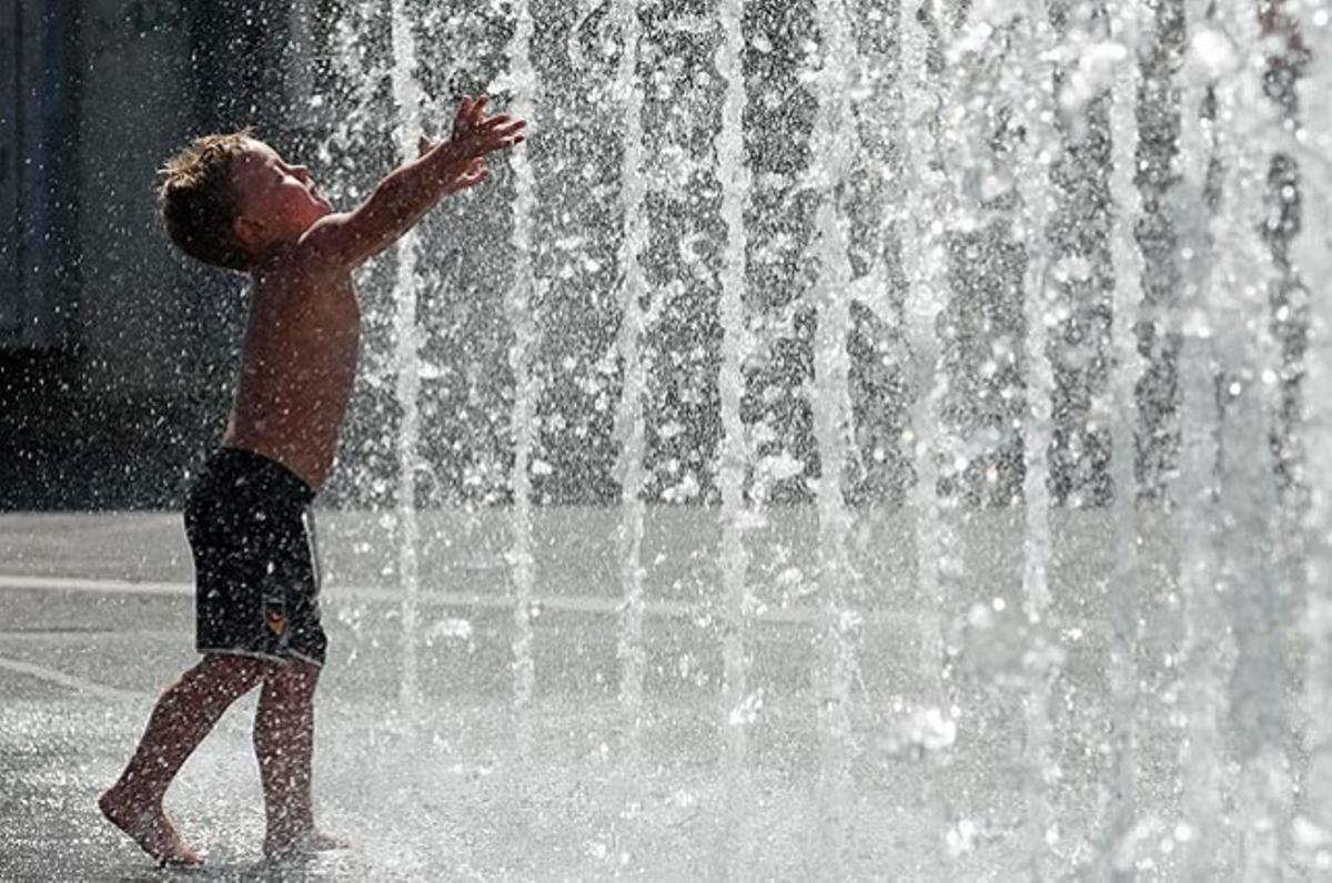 Un nen juga amb l’aigua d’una font pública en una plaça de Viena. S’espera que les temperatures arribin als 36ºC a tot Àustria, durant l’onada de calor.