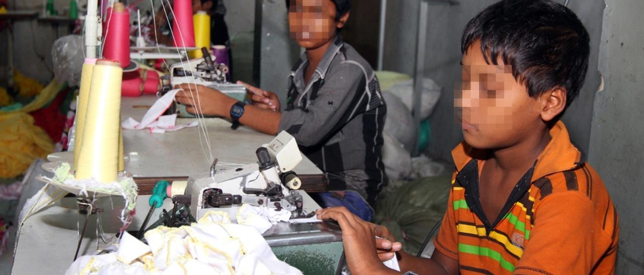 Dos niños realizan trabajos en una fábrica textil.