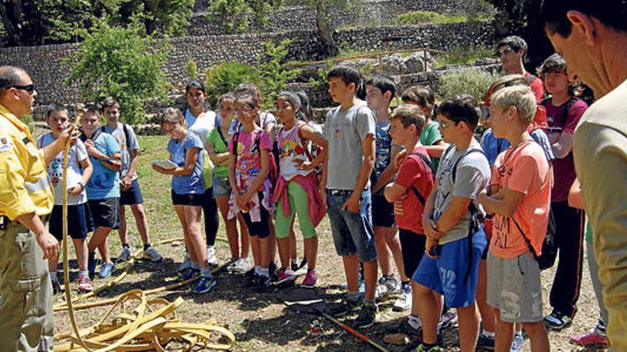 Uno de los agentes del servicio antiincendios forestales explica a unos adolescentes cómo se utiliza el material de extinción.