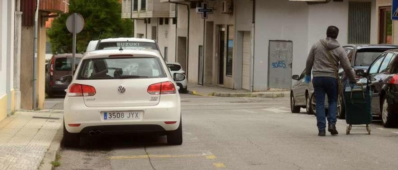 Un vecino caminando por la calle para evitar la estrecha acera en el barrio de Os Duráns. // Noé Parga