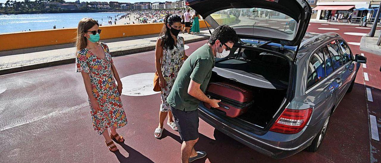 Unos visitantes introducen las maletas en el coche el pasado agosto en Sanxenxo.
