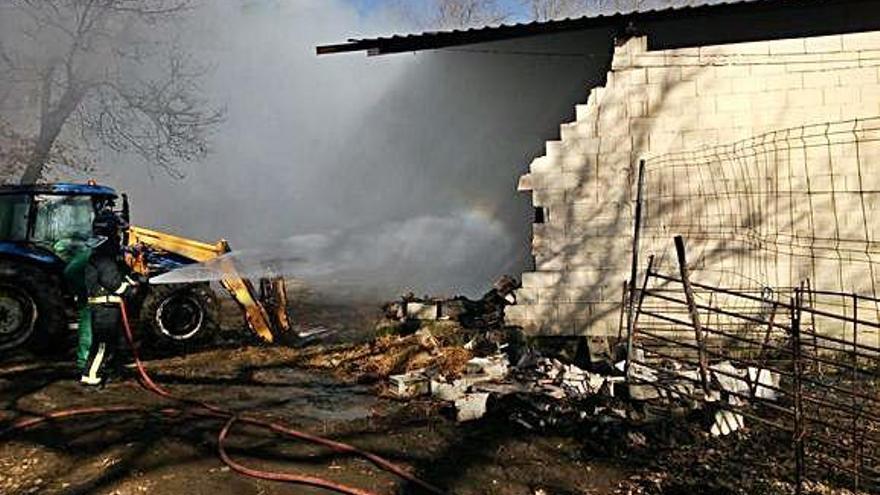 Un bombero trata de sofocar el fuego en la nave, medio derruida.