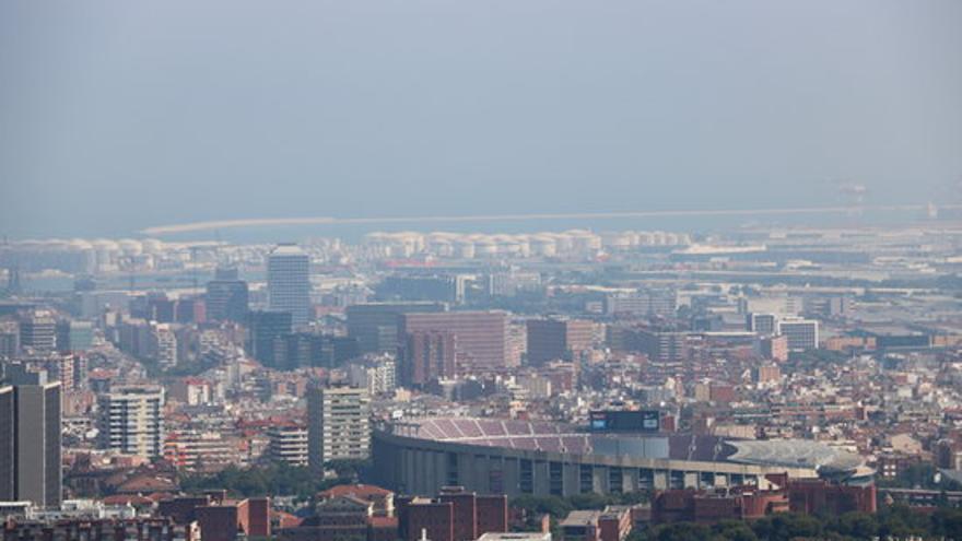 Barcelona amb el Camp Nou en primer pla i el port de fons amb boira per pol·lució al fons