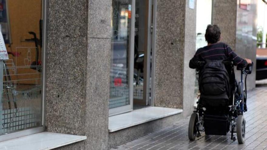 Un discapacitado pasa junto a un establecimiento con un escalón en la puerta.