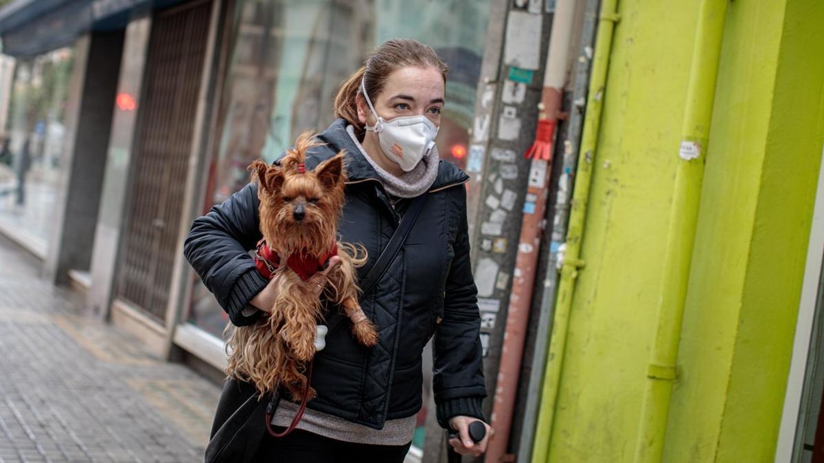 Una mujer camina por la calle con su perro.