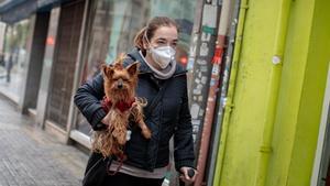 GRAFCVA3035. VALENCIA, 16/03/2020 Una persona con mascarilla camina por la calle con un perro en brazos. EFE/ Biel Aliño