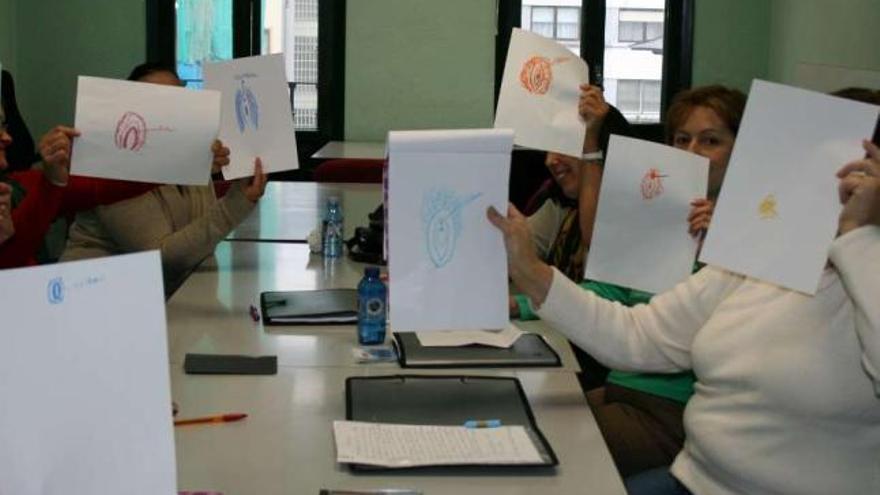 Participantes en uno de los talleres sobre sexualidad de Acadar muestran sus dibujos de una vagina. / acadar