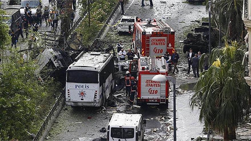Bombers al costat de l&#039;autobús afectat per l&#039;explosió.