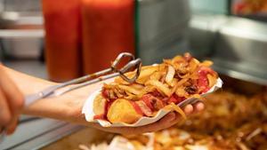Un trabajador prepara una salchicha con patatas en un restaurante de comida rápida de Berlín