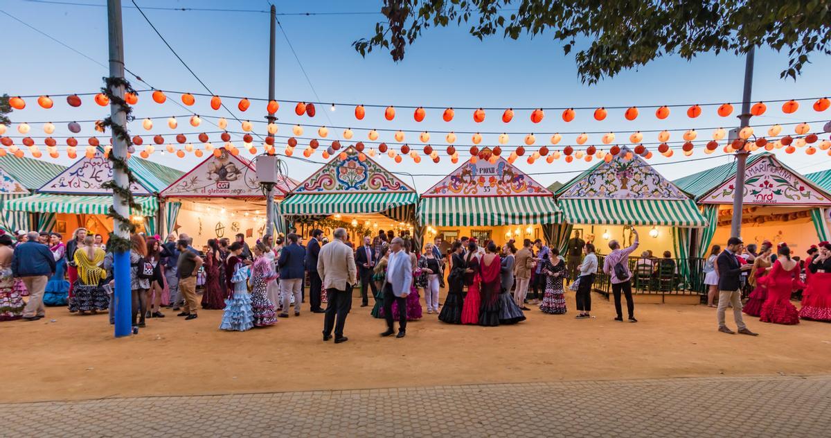 Gente paseando, bailando y bebiendo en las casetas de la Feria de Abril de Sevilla