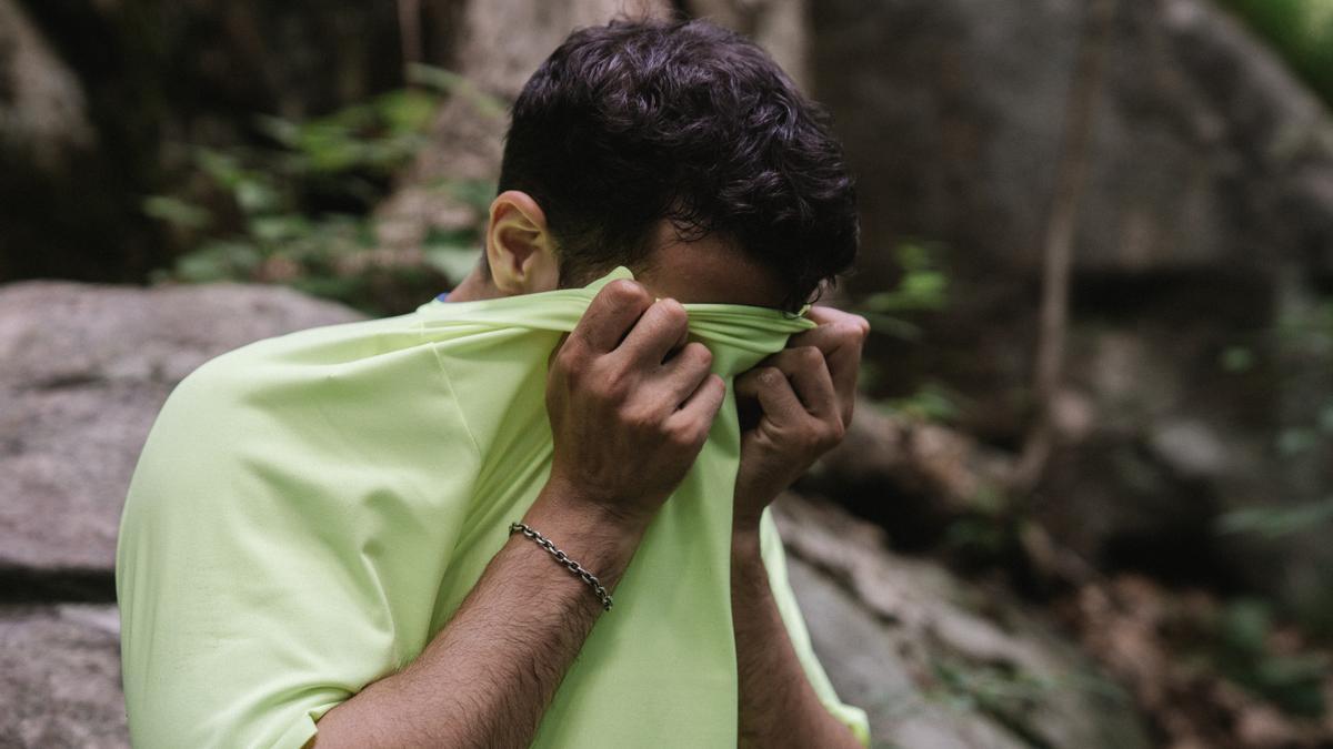 Hombre joven limpiando el sudor con la camiseta