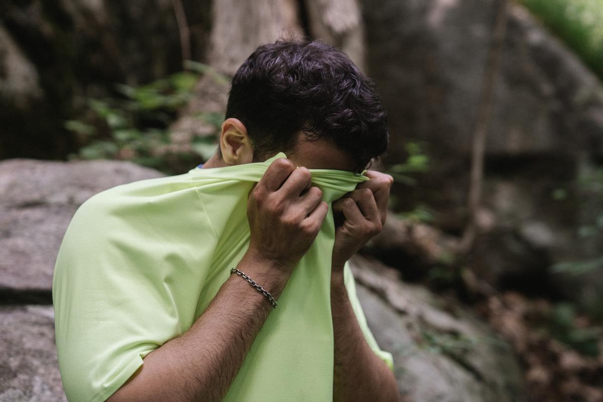 Hombre joven limpiando el sudor con la camiseta