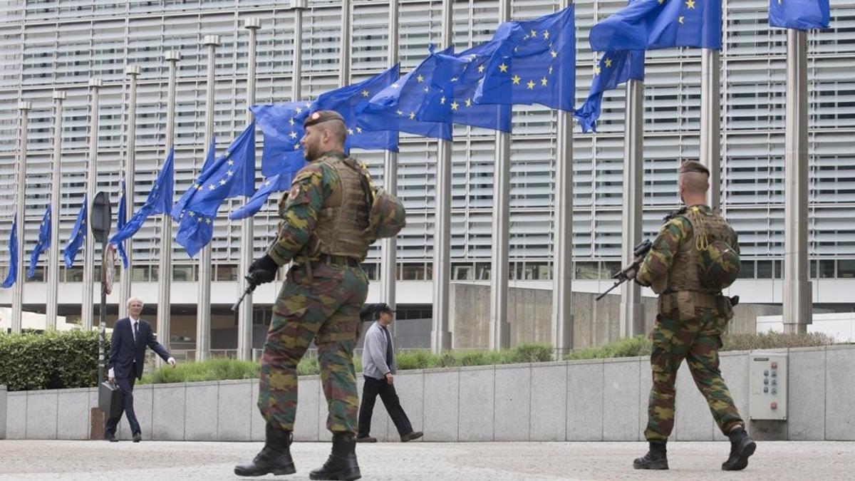 Soldados belgas patrullan junto a las banderas de la UE que ondean a media asta por el atentado de Manchester, el 23 de mayo, en Bruselas.