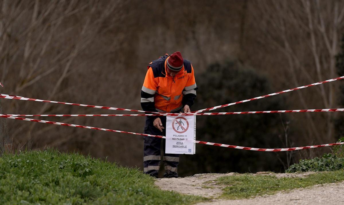 Un guarda coloca un cartel de 'prohibido pasar' en una de las orillas del río Manzanares a la altura de El Pardo.