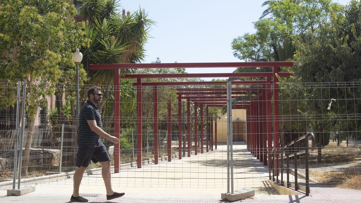 Una persona pasa por delante de la polémica estructura instalada frente a la ermita de Villafranqueza