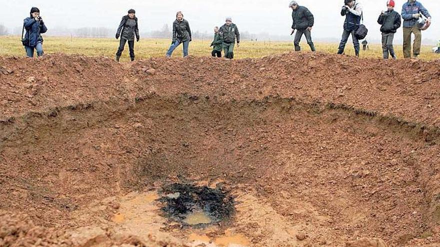 Científicos y periodistas observan, ayer, el cráter que habría causado el meteorito, en Letonia. / v.kalnina