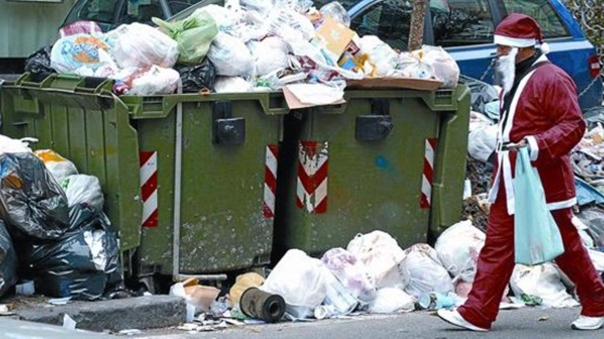 En plena Navidad 8Un hombre vestido de Santa Claus pasa junto a basuras acumuladas en una calle de Nápoles.