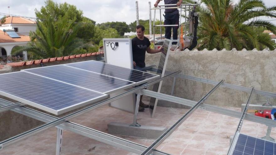 Dos operarios instalan placas solares en un tejado.