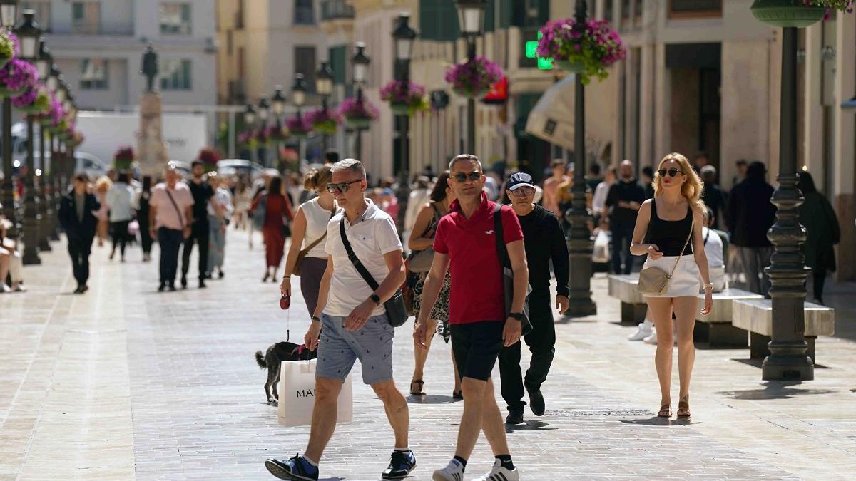 Una imagen de turistas con sus compras en la calle Larios de Málaga, una de las principales vías comerciales de España.