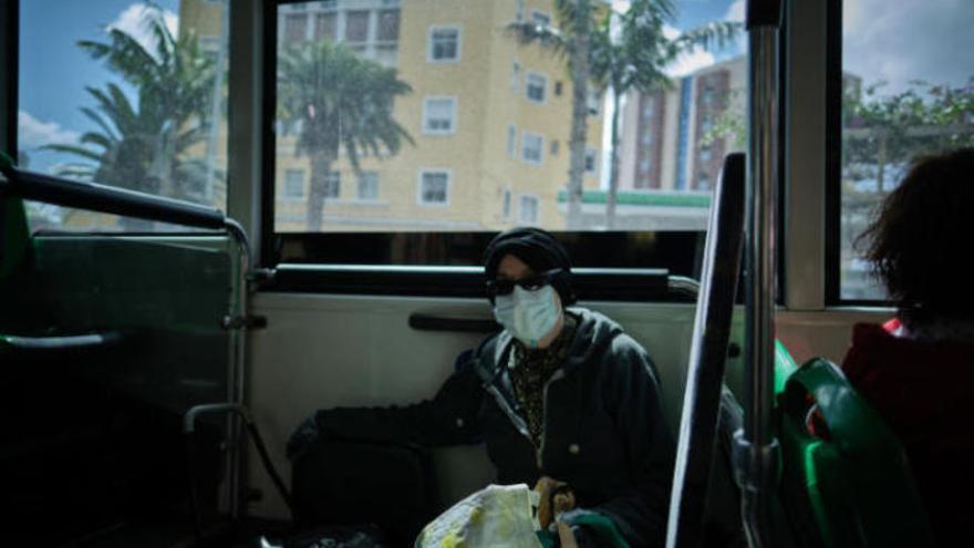 Una usuaria en la guagua equipada con mascarilla.