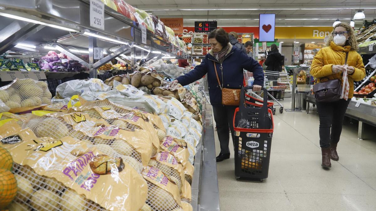 Clientas compran frutas y verduras en un supermercado.