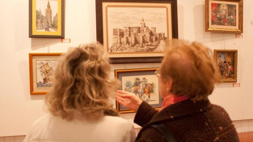 Dos mujeres observan algunas de las obras expuestas, entre ellas una recreación del Castillo de Benavente.