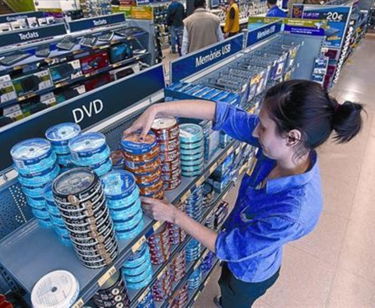 Una dependenta col·loca a la prestatgeria DVD per gravar en una  botiga d’informàtica de Barcelona.