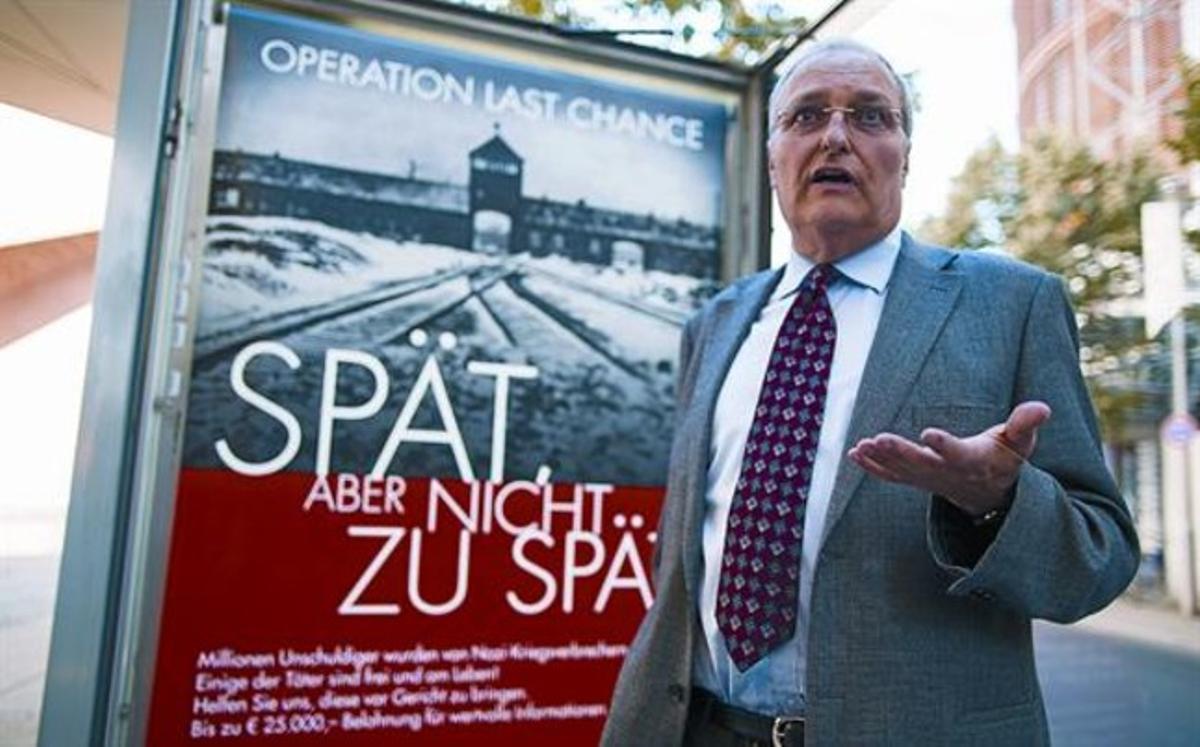 El ’caçanazis’ Efraim Zuroff parla amb els reporters davant un cartell de la campanya, ahir, a Berlín.