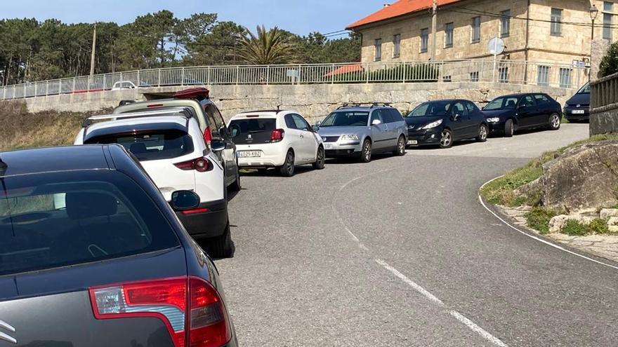 Una carretera que baja hacia A Lanzada, con los coches ocupando un carril, como si fuera verano.