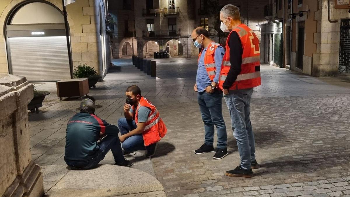 Tres voluntaris de Creu Roja parlant amb una persona al Pont de Pedra de Girona.  | CREU ROJA A GIRONA