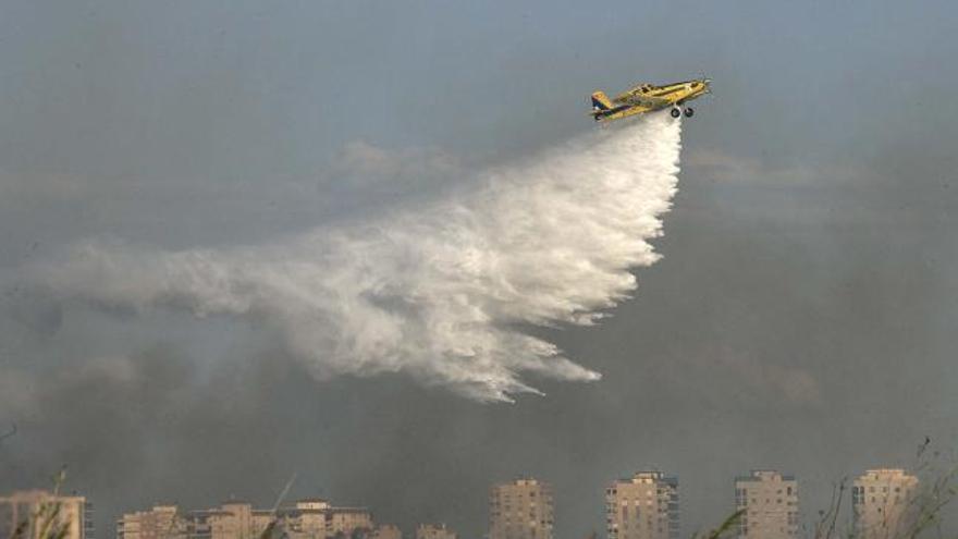 Un helicóptero descarga agua sobre el incendio de Benicàssim, cerca de una zona urbanizada.