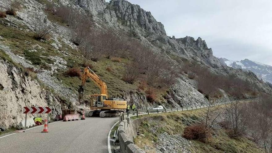 Dos operarios, junto a una máquina retroexcavadora, al inicio de los trabajos en la carretera AS-264.