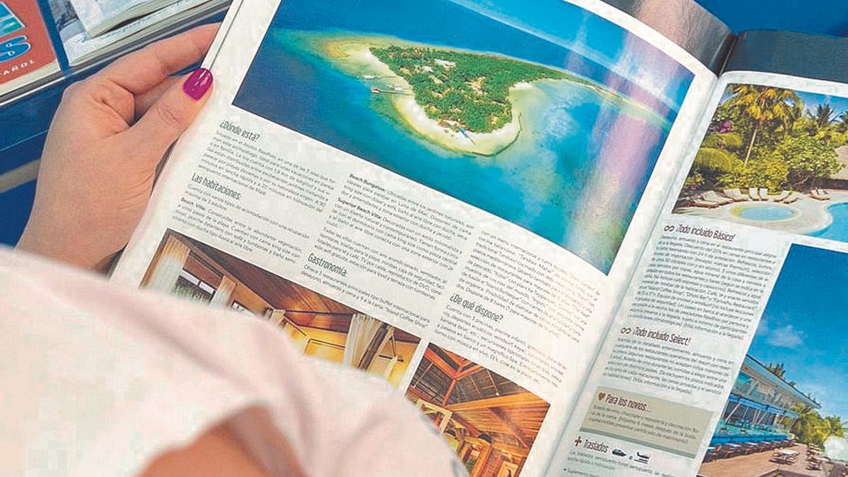 Una clienta observa un folleto en una agencia de viajes. | RAFA ARJONES