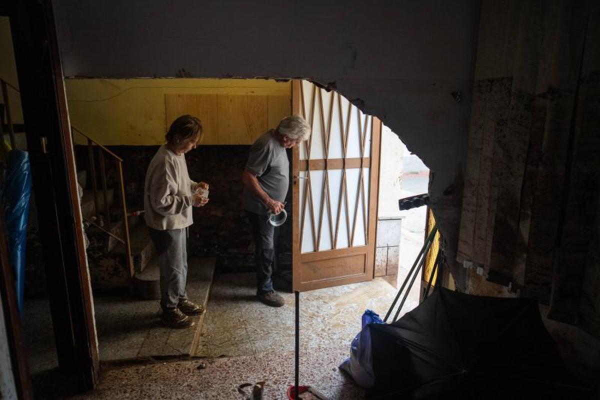 Un boquete entre la habitación y el pasillo deja ver a Xisqueta y Antonio Mirall, vecinos de Godall, que apuntalan la puerta con maderas para protegerse de las futuras lluvias.