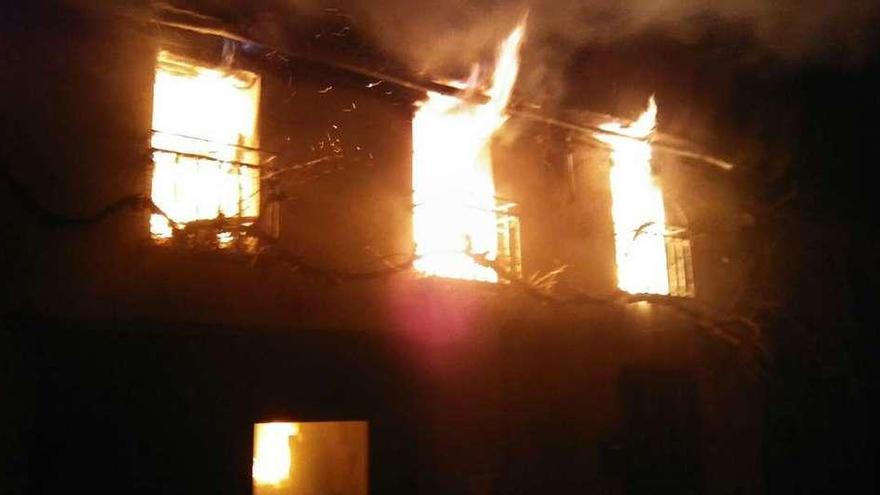 Las llamas asoman por las ventanas del piso superior de la vivienda incendiada en Vegalatrave.