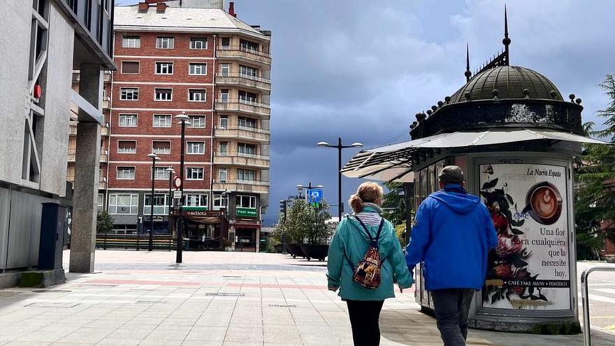 Una pareja pasea por la calle Leopoldo Calvo-Sotelo, en Oviedo, mientras luce el sol; al fondo, nubes de tormenta. | C. V.