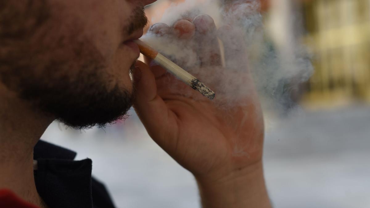 Un hombre fuma un cigarrillo en la vía pública en Córdoba.